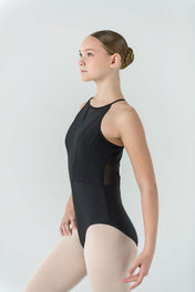 A young ballerina, her hair in a bun, stands poised against a light gray background wearing the elegant Ava Leotard and pale tights.
