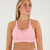 A woman with long blonde hair models the Bonbon Vivid Pink Top with adjustable straps, looking to the side against a plain white background.
