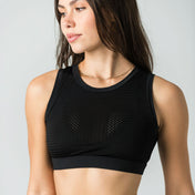 A woman with long brown hair wears the WOW Mesh Top, featuring a built-in bra, and black high-waisted leggings as she looks to the side against a plain light gray background—ideal for elevating any dance wardrobe.