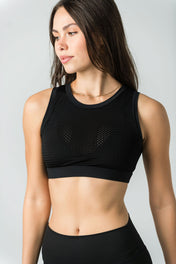 A woman with long brown hair wears the WOW Mesh Top, featuring a built-in bra, and black high-waisted leggings as she looks to the side against a plain light gray background—ideal for elevating any dance wardrobe.