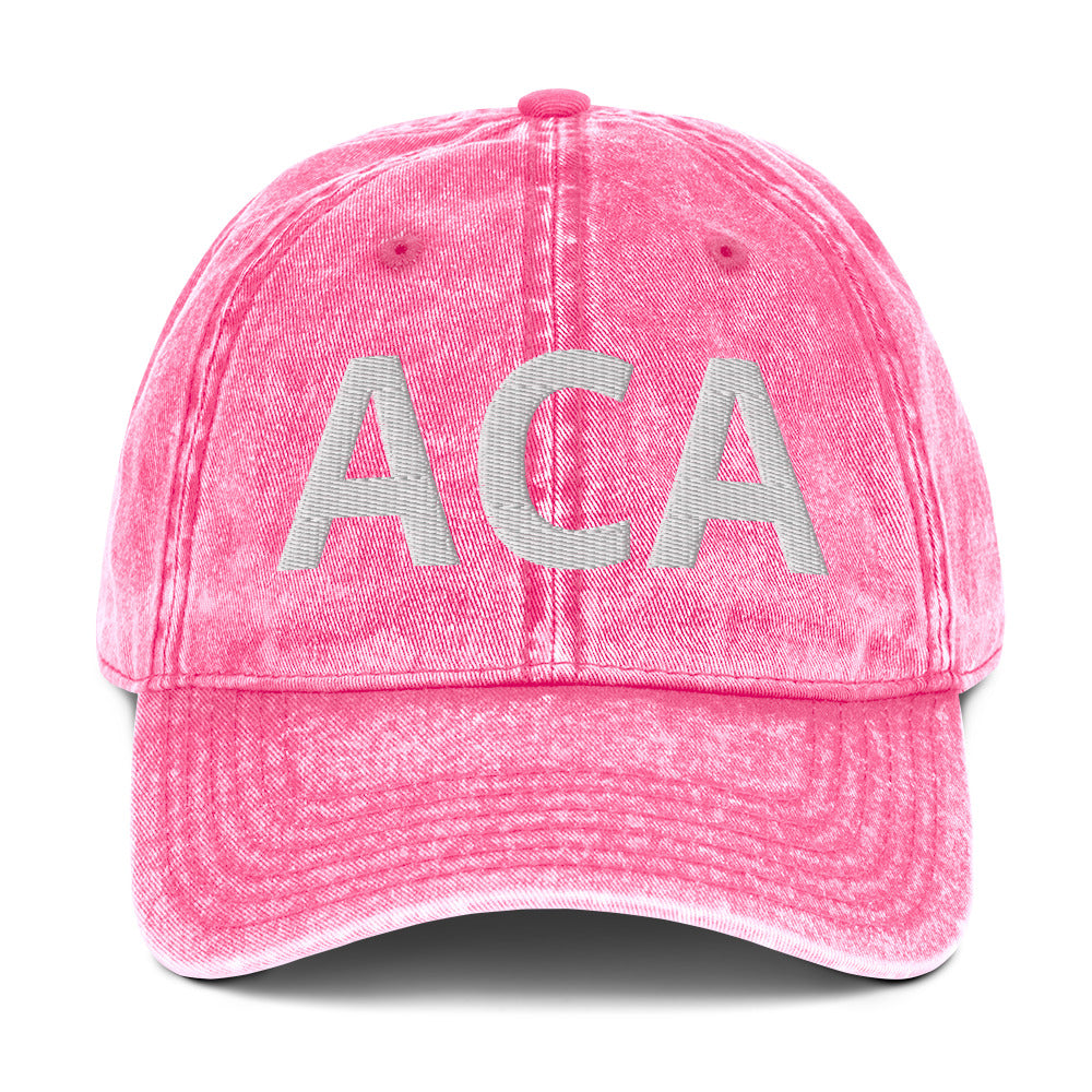 The Vintage Cap - Girly Pink is a distressed cotton twill hat in pink with large white ACA embroidery on the front and an antique brass buckle for adjustable fit.